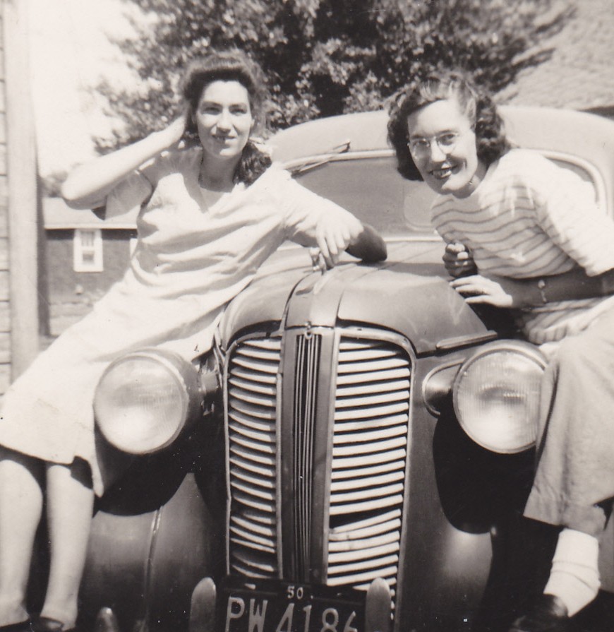 Dorothy Hogan and Mary Doan sitting on the hood of a car