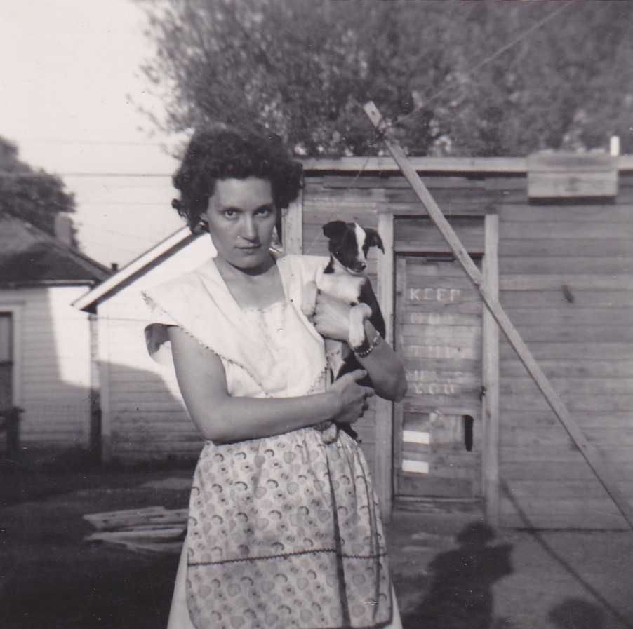 Mary Doan holding a small puppy in front of a wooden shed